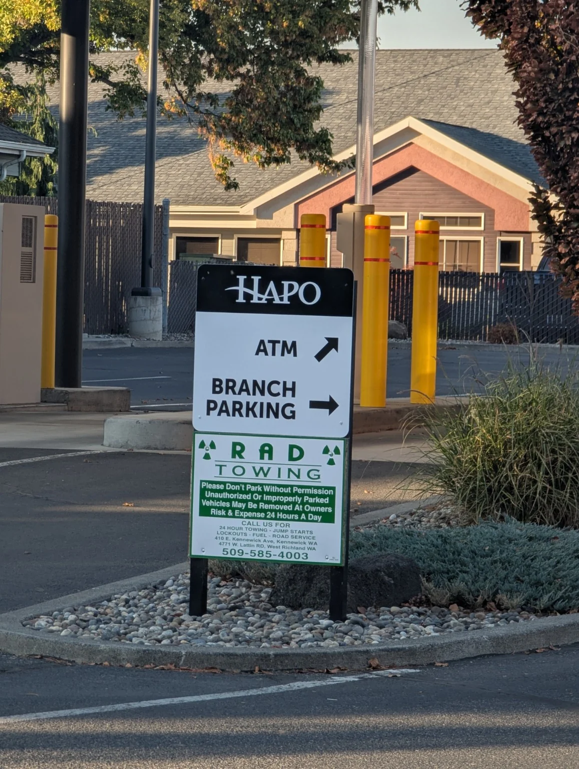 HAPO ATM and branch parking sign with directional arrows, mounted above a separate towing notice
