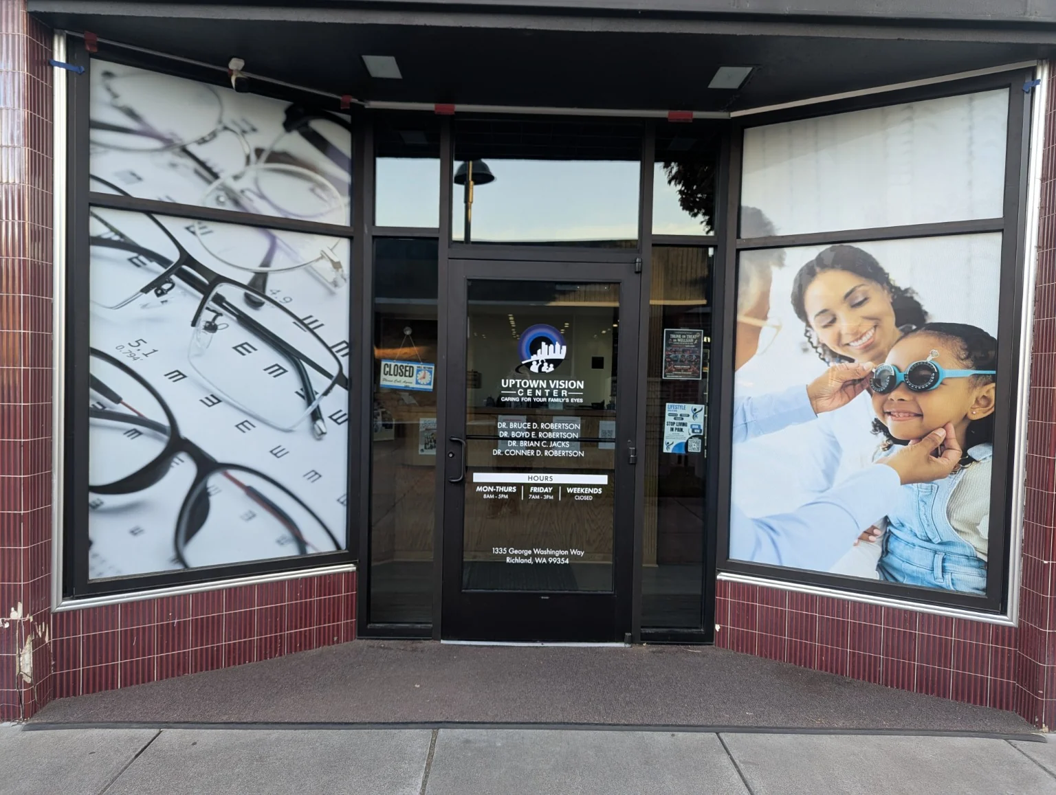 Uptown Vision Center entrance framed by full-height eyeglass and eye-exam window graphics, with white door lettering